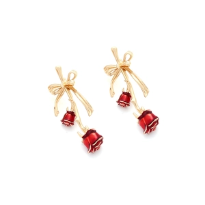 Detail of elegant gold bow earrings with vibrant red dripping glaze rose pendants