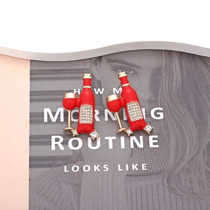 Close-up of red enamel wine bottle and glass earrings with sparkling rhinestones
