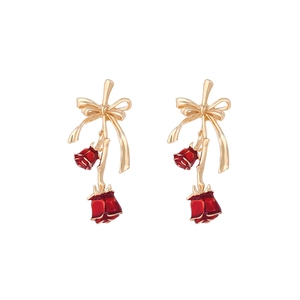 Elegant gold bow earrings with cascading red enamel roses and leaves on a white background