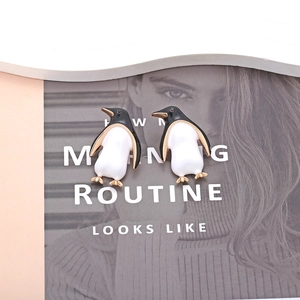 Chic penguin earrings with black and white enamel finish on fashion magazine background