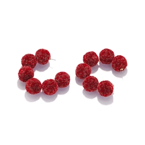 Detailed shot of dark red plush pom-pom C-shaped hoop earrings with gold metal studs