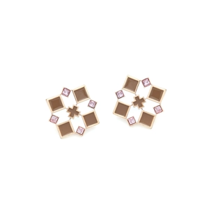 Detail of geometric gold earrings with brown enamel squares and pink crystal accents