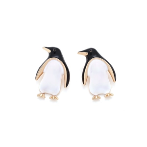Detailed view of cute penguin earrings with black and white enamel and golden metal finish