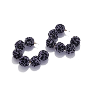 Detail of C-shaped hoop earrings featuring purple leopard print faux fur pom-poms