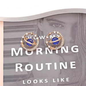 Boucles d'oreilles planète bleue dorées avec étoiles et lune sur un magazine