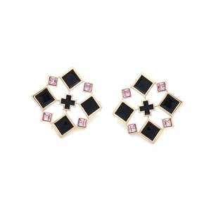 Detail of geometric earrings featuring gold frames, black enamel, and pink crystals