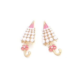 Macro detail of alloy umbrella earrings with pearls, pink enamel and a bow tie accent