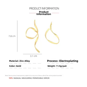 Detail of gold asymmetric metal ribbon earrings with 7.8cm height and 3.1cm width