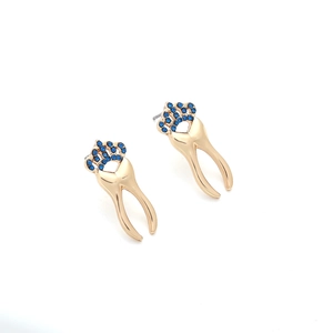 Detail of gold tooth-shaped stud earrings with blue rhinestone crown embellishments