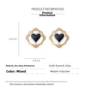 Close-up of geometric gold-plated heart earrings with black enamel and sparkling rhinestones