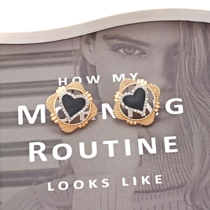 Elegant gold heart earrings with black enamel and rhinestones on a stylish magazine