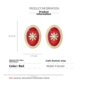 Detailed close-up of oval vintage red enamel earrings with crystal center and gold border