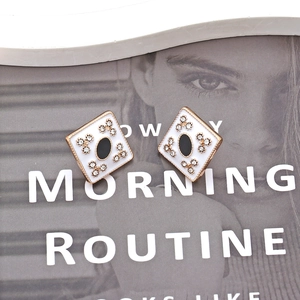 Macro detail of geometric enamel earrings with crystals and vintage gold finish
