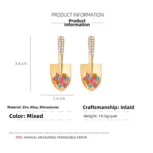 Close-up of shovel-shaped gold alloy earrings with colorful rhinestones and pearls