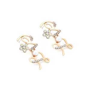 Detail of gold LOVE earrings with pearls and rhinestones on a white background
