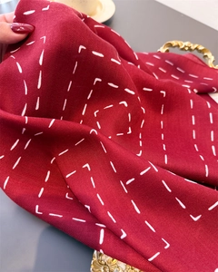 Detail of burgundy herringbone scarf featuring a geometric dotted line pattern texture