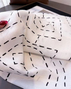 Macro detail of geometric herringbone texture on lightweight white cotton-linen scarf