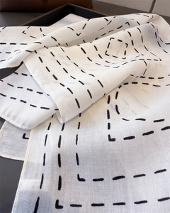 Detail view of cotton-linen feel white scarf with black geometric dashed line patterns