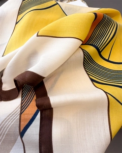 Detail of herringbone weave fabric with yellow and brown geometric patterns on a scarf