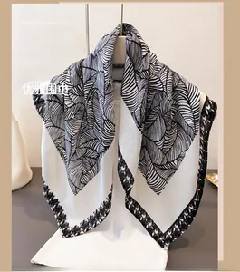 Close-up of lightweight scarf with leaf vein pattern and geometric border detail