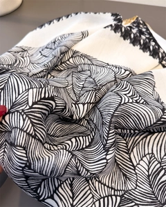 Detailed view of the wavy black and white palm leaf patterns on soft silk scarf fabric