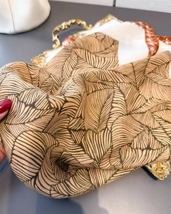Detail of soft palm leaf pattern scarf on vintage gold tray with elegant silk texture