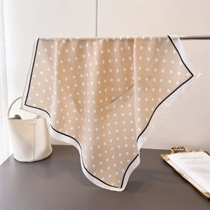 Close-up of elegant polka dot scarf with silky texture and contrasting black white border