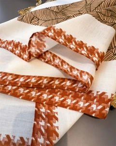 Detail of herringbone linen-textured scarf with orange houndstooth and palm leaf patterns