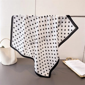 Classic black and white polka dot square scarf draped on a metal display stand