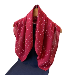 Lightweight red scarf with white geometric dotted lines hanging on a wooden hanger
