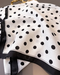 Detail of classic black polka dots on soft white woven scarf with elegant black stitched edges