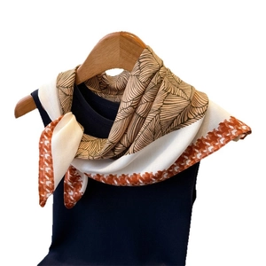 Brown leaf texture and orange houndstooth pattern square silk scarf on wooden hanger