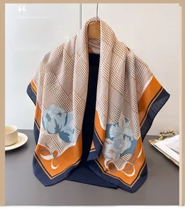 Détail d'un foulard en soie avec motifs de fleurs orange et texture en pied-de-poule