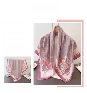 Détail d'un foulard en soie avec motif pied-de-poule et imprimés roses en rose poudré