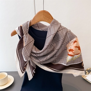 Détail d'un foulard en soie à motif pied-de-poule et imprimé fleuri sur haut marine