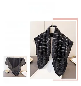 Detail of black silk-like scarf featuring white polka dots and elegant paisley border
