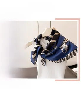 Detail of silk-feel scarf featuring zebra print and contrast stripe edges on blue fabric