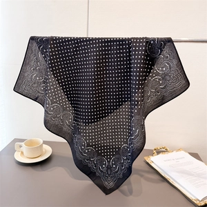 Elegant black square scarf with white polka dots and paisley patterns hanging on a stand