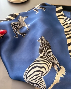 Close-up of navy blue silk scarf with realistic zebra print and smooth satin texture