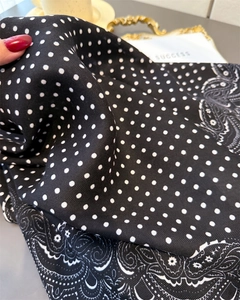 Detailed view of paisley and polka dot patterns on a soft black cotton linen scarf