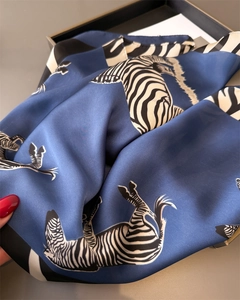 Close-up of deep blue silk scarf featuring realistic black and white zebra print patterns