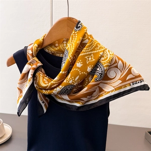 Carré de soie élégant motif paisley jaune moutarde et noir sur cintre en bois texturé