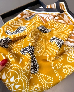 Gros plan du foulard en soie jaune gingembre avec motif cachemire et texture de luxe