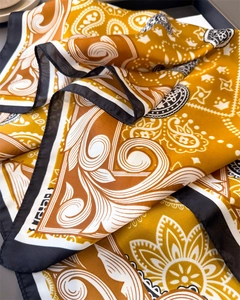 Détail d'un foulard en satin de soie à motif cachemire jaune gingembre et bord noir