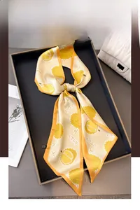 Détail d'un foulard étroit en soie jaune crème avec motif durian noué en boucle