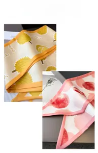 Détail d'un foulard en soie avec imprimé durian jaune et fruits roses et bord roulé