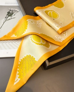 Détail d'un foulard en soie jaune et blanc avec motifs de durian sur fond de magazine