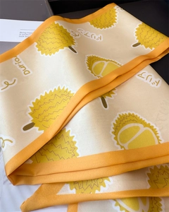 Détail d'un foulard en soie jaune avec motifs de durian et texture de tissu lisse