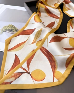 Détail d'un foulard en soie avec motif de fruits jaunes et imprimés de feuilles oranges