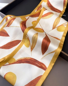 Détail d'un foulard en soie avec imprimés de feuilles d'automne et bords jaunes